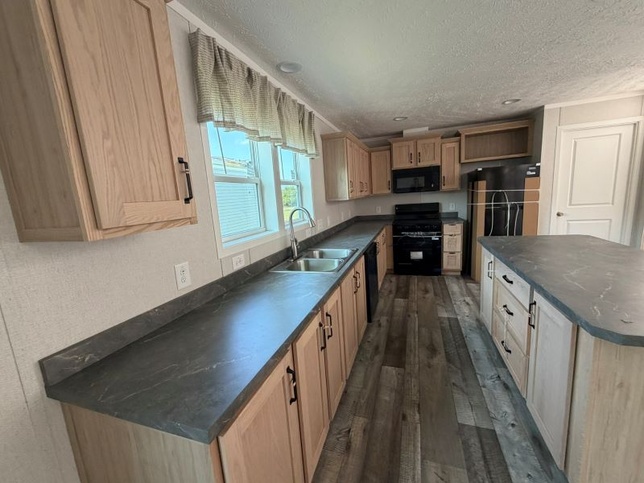 Stainless steel sink with black stove, microwave, dishwasher, and refrigerator. 