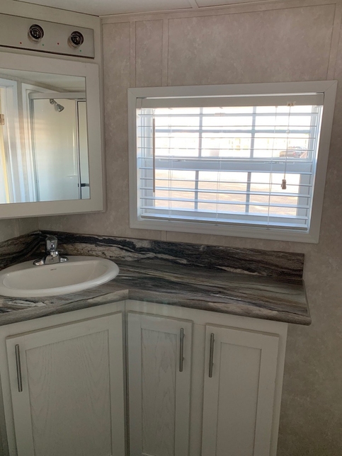 Spacious bath countertop and lighted mirror in the 100152 Country Manor from Fairmont Homes.