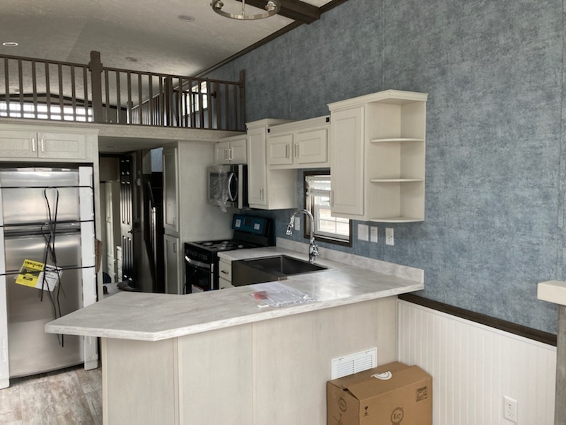 Beautiful white cabinetry and blue-gray walls with wrap around kitchen countertop in the 100152 Country Manor from Fairmont Homes.