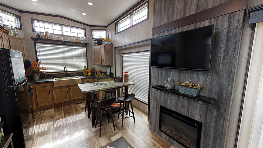 Large entertainment center with electric fireplace and functional front kitchen in the 100170 Country Manor from Fairmont Homes.