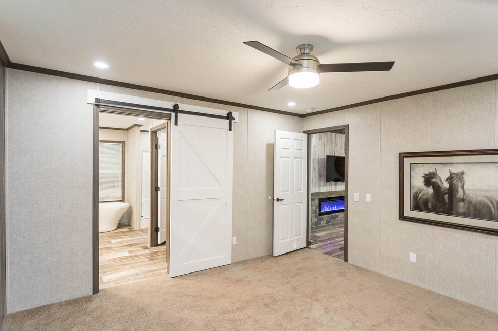 This master bedroom has an attractive and dramatic sliding door between the master bedroom and the master bath in the Inspiration Hyatt Model 186046, a manufactured home by Fairmont Homes.