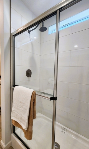 The beautifully appointed 54" ceramic tile shower features a matte black rain showerhead and a transom window that bathes the space in natural light, creating a spa-inspired retreat.

#ABetterWayToBuild